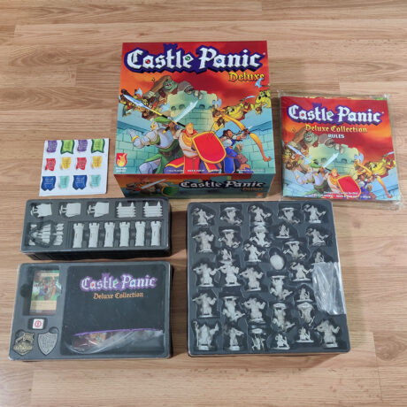 Castle Panic Deluxe Box surrounded by vac trays on a wooden floor