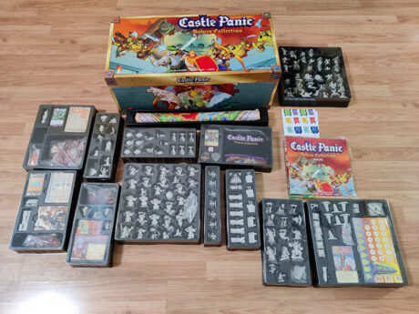 Castle Panic Deluxe Collection surrounded by vac trays on a wooden floor